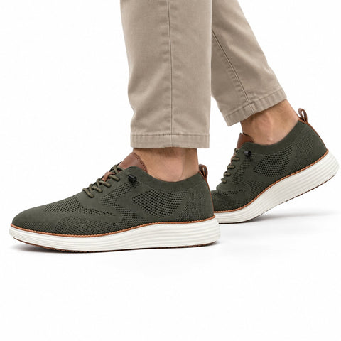 Strider olive men's casual sneakers with knit uppers and thick white soles styled with khaki trousers for a discreet height boost