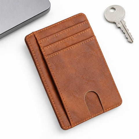The Modern Cardholder in brown leather with multiple card slots and a slim profile displayed beside a laptop and keys for minimalist everyday carry