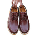 Brown leather shoes with laces held by a hand on a white background