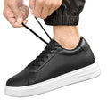 Person wearing a black leather sneaker with white sole, tying the lace.