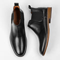 Wellington black leather men's dress shoes with a discreet height boost, featuring elastic side panels and stacked wooden heels for a sleek, comfortable elevator shoe design.