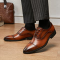 Brown dress shoes worn with striped pants on a wooden floor.