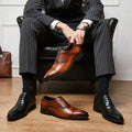 Man sitting in a chair wearing a suit and shoes, with additional shoes displayed on the floor.