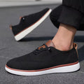 Strider black men's sneakers with discreet height boost, featuring breathable knit upper, brown leather accents, and white sole designed for comfortable all-day wear.