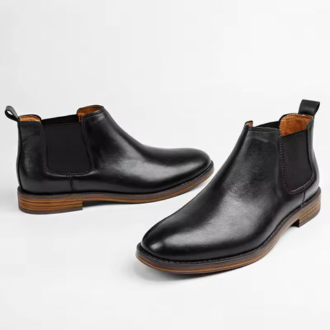 Pair of black leather Wellington boots with discreet height increasing design, elastic side panels, and brown stacked heels offering comfort and style for men.