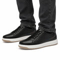 Brooklyn black casual sneakers with white platform soles and a discreet height boost shown worn with jeans for a modern elevated look