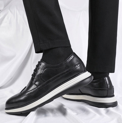 Black leather shoes with white soles worn by a person on a white background