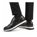Hartford black leather elevator dress shoes with white layered soles shown on a model featuring a polished lace up design and discreet height boost