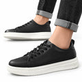 Hawthorn black casual shoes with thick white soles, shown worn with cuffed jeans, featuring a discreet height boost and modern sneaker styling