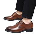 Brown polished men's dress shoes with black sole, worn with black trousers, featuring discreet height boost and hidden internal lift for everyday comfort, Regent model.