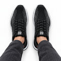Retro33 black height increasing sneakers with textured knit uppers and lace up design shown worn with dark jeans for a discreet lift and modern style