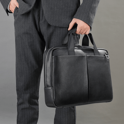A person holding The Modern Briefcase in black, showing the sturdy handles and structured shape.