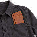 The Modern Cardholder in brown leather with multiple card slots shown in the chest pocket of a black button up shirt